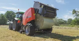 A KUHN FB 3135 AUTOMATE, ami éppen egy fóliával kötött körbálát ad ki.