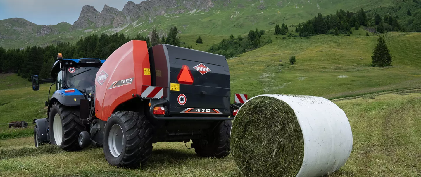 KUHN FB 3130 fix körbálázó fóliás kötéssel, ami éppen körbálákat gyárt a hegyekben