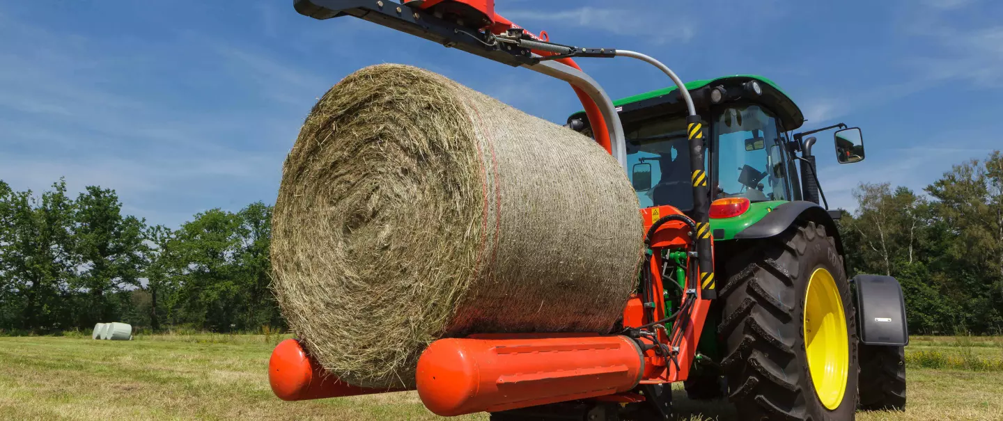 RW 1200 függesztett bálacsomagoló csomagolandó hengerbálát ragad meg.