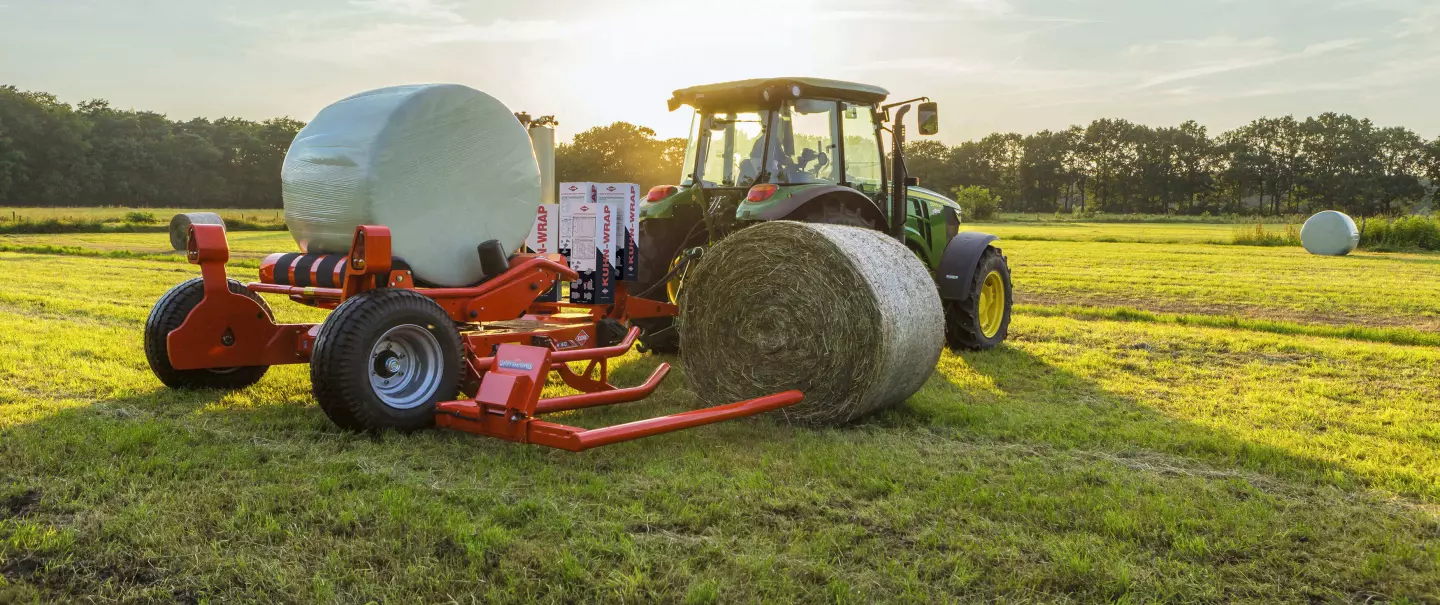 RW 1610 vontatott hengerbála-csomagoló egy bála felvétele és egy másik bála csomagolása közben.